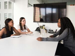 Two black women and one white woman in a boardroom