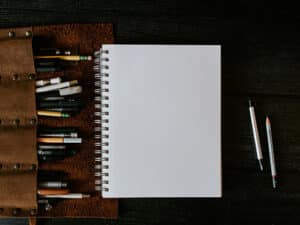 empty notebook with pencils on dark wood table