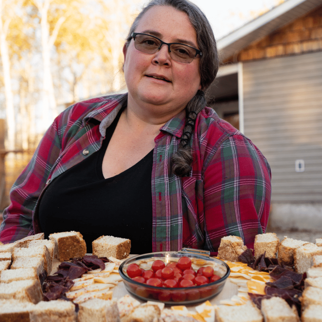 Woman in plaid shirt sitting in front of bannock tray