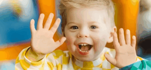 Blonde child facing camera with hands up