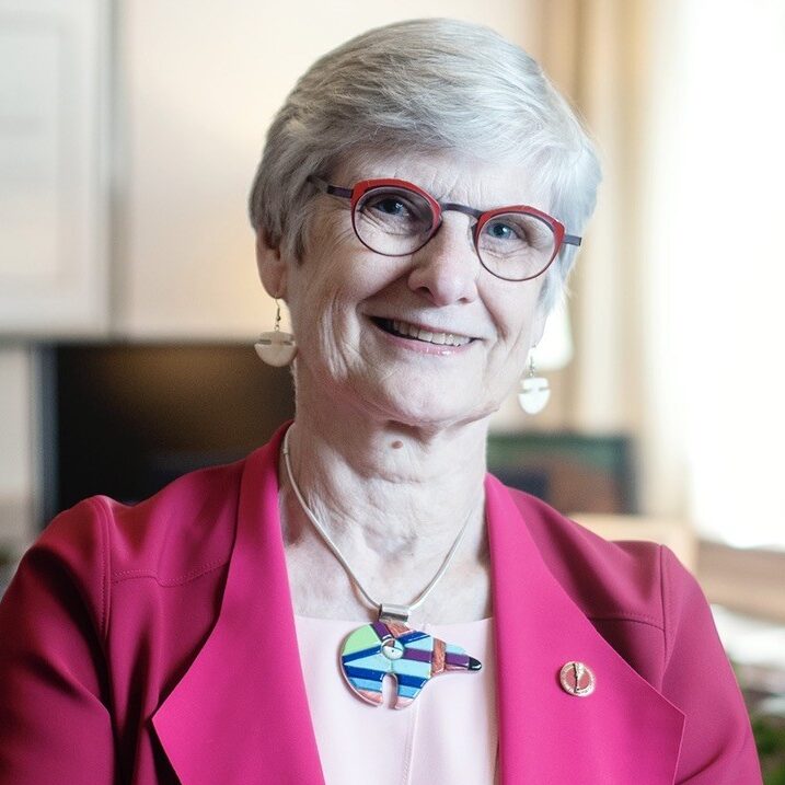 Woman with short hair in pink blazer facing camera and smiling