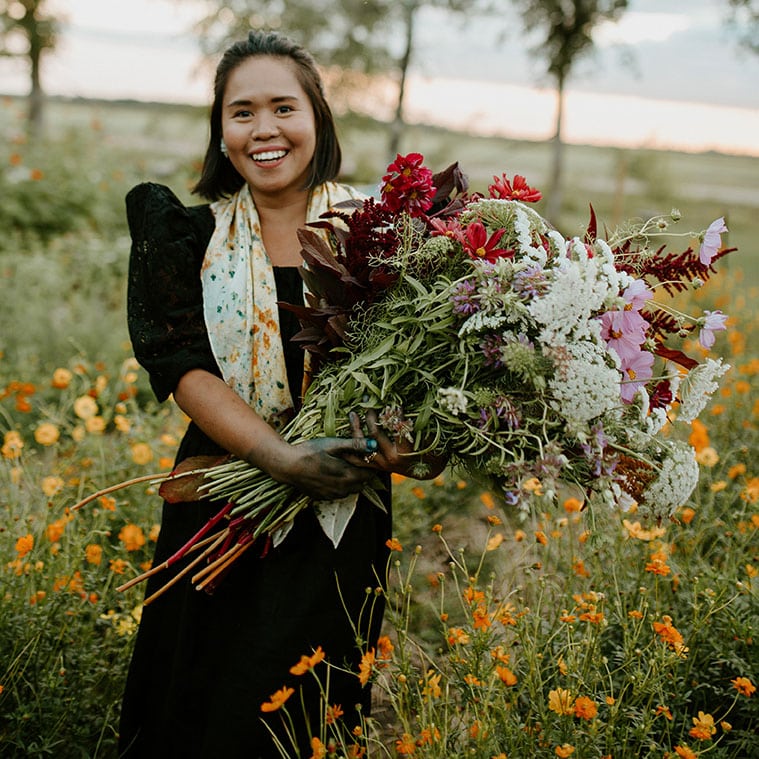 Woman in field holding bundle of flowers