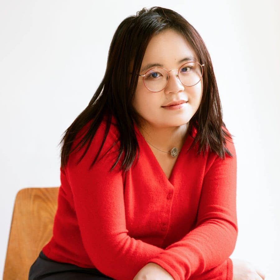 a woman wearing glasses smiles slightly